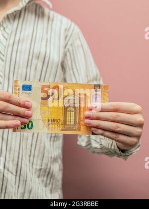 Finanzielle Unterstützung für das Kind. 50 Euro in den Händen eines Kindes als Konzept der materiellen Unterstützung für Kinder, Unterhaltszahlungen, Investitionen. Stockfoto