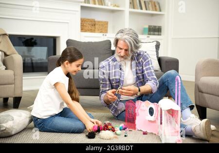 Liebevoller Großvater und entzückendes kleines Mädchen Enkelin, die mit Spielzeug spielt, während sie auf dem Boden des Wohnzimmers sitzt, älterer Opa, der ein Wochenende mit Kind verbringt, während er zu Hause die gemeinsame Spielzeit genießt Stockfoto