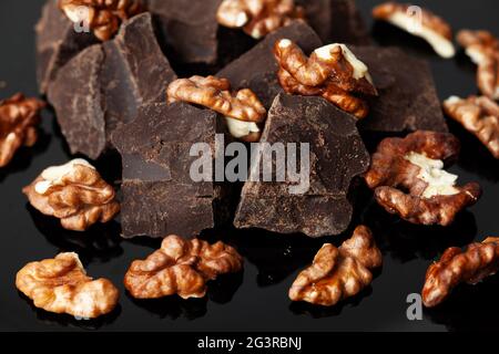 Broken Bio hausgemachte dunkle Schokolade mit Walnüssen um sie herum. Nahaufnahme. Stockfoto