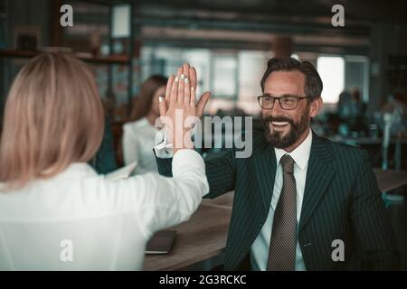 Mann in Anzug und Brille gibt einem Mädchen in einer weißen Bluse fünf Kollegen. Die Beziehung der Kollegen ist ein Konzept. Hohe Qualität Stockfoto