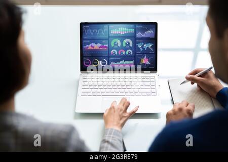 Zwei Analytiker, die KPI-Dashboard auf einem Laptop verwenden Stockfoto