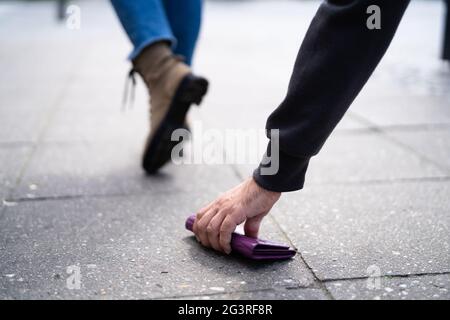 Dieb Pflückt Mit Geld Verlorene Persönliche Brieftasche. Zu Fuß Auf Der Straße Stockfoto