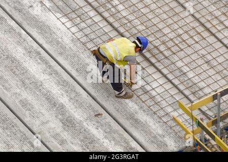 Arbeiter auf einer Baustelle (Gebäude), der die Betonbewehrung auf dem Fundament eines Gebäudes anpasst Stockfoto