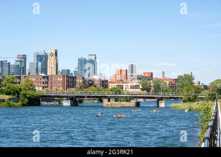 Blick auf die Innenstadt von Montreal und den Atwater Market vom Lachine Canal aus mit Booten und Kajaks, die entlang schwimmen Stockfoto