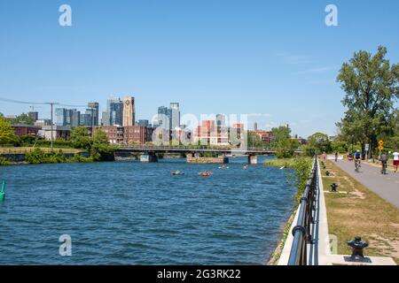 Blick auf die Innenstadt von Montreal und den Atwater Market vom Lachine Canal aus mit Booten und Kajaks, die entlang schwimmen Stockfoto