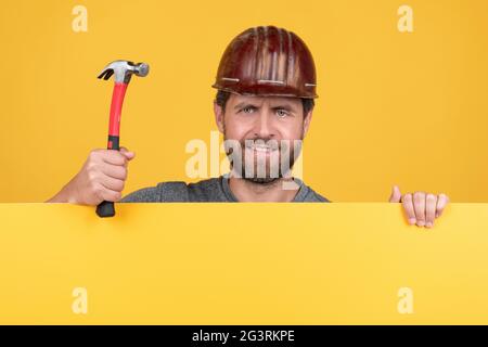 Arbeiterwerbung. Ankündigung. Glücklicher Arbeitstag. Lächelnder Mann im Helm mit Hammer. Stockfoto