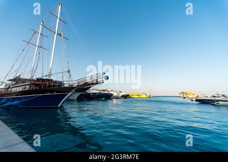 Leere Pier ohne Menschen mit einem Segelboot mit modernen Schiffen und Booten im Roten Meer Ägypten Hurghada Stockfoto