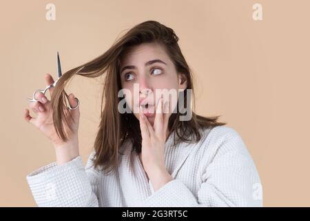 Traurige Frau, die ihre Haare mit einer Schere schneiden ließ. Schöne Frau in Panik wegen Haarausfall. Frau mit Haarausfall Problem. Stockfoto