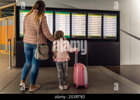 Entkokende Silhouette der Familie, des jungen Mädchens und ihrer Mutter auf dem Flughafenterminal Stockfoto