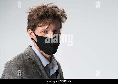 Moderner ernster Mann in schwarzer Gesichtsmaske auf weißem Hintergrund. Kopf- und Schulterporträt Stockfoto