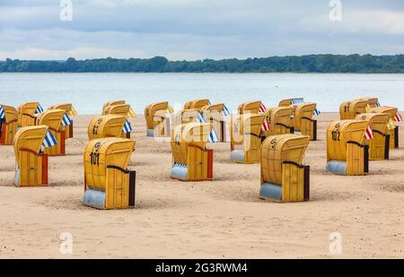 Bunte Holzkuppenliegen (Strandkorb) an einem sandigen Ostseestrand im Seebad Travemunde, Bezirk Lübeck, Schleswig-Holstein, Ge Stockfoto