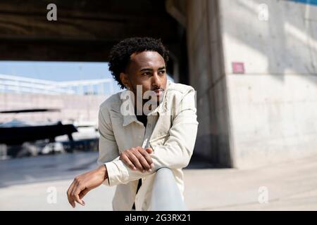 Afro-Mann lehnte sich an Geländer, während er an einem sonnigen Tag wegschaute Stockfoto