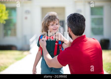 Vater hilft Sohn bereit zur Schule. Vater unterstützt und motiviert Sohn. Kind geht zur Grundschule. Stockfoto