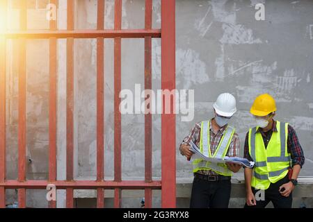 Der Ingenieur hält die Blaupause in der Hand und diskutiert das Projekt mit dem Bauleiter Stockfoto