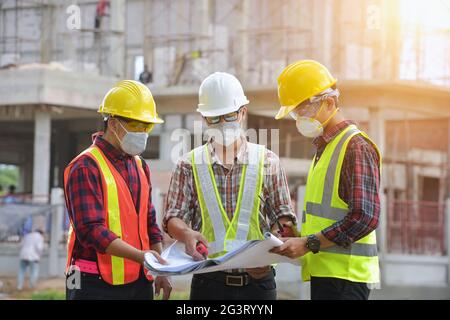 Der Ingenieur hält die Blaupause in der Hand und diskutiert das Projekt mit dem Bauleiter Stockfoto