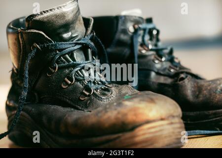 Alte abgenutzte Arbeitsstiefel mit Schnürung. Lederschuhe, die repariert oder ersetzt werden müssen. Nahaufnahme Stockfoto