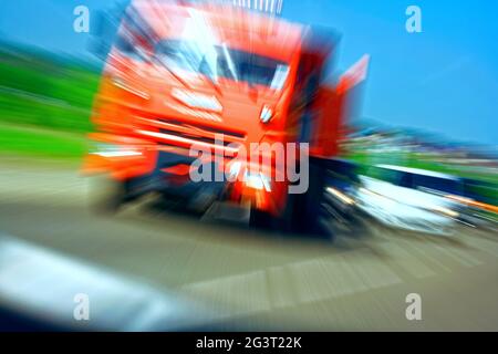 LKW mit rotem Fahrerhaus auf der Straße in Bewegung. Unfallrate. Blick aus dem Taxi des Autos Stockfoto