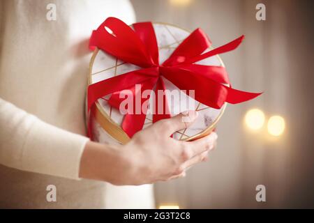 Crop weiblich zeigt Geschenkbox mit roter Schleife Stockfoto