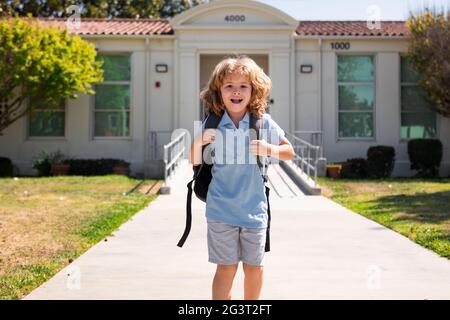 Kinderpuppe mit Rucksäcken im Park in der Nähe der Schule. Schuljunge mit Rucksäcken im Freien. Wissenstag. Schuluniform. Stockfoto