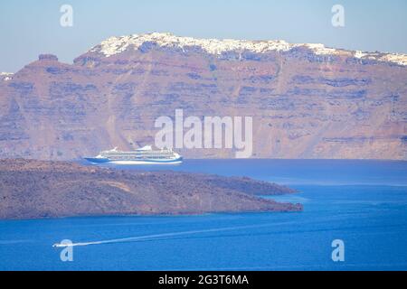 Großes Kreuzfahrtschiff vor der sonnigen Küste von Santorini Stockfoto