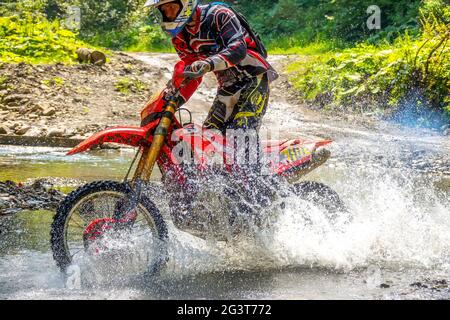 Motorrad Enduro und Athlete in Wasser Spray Stockfoto