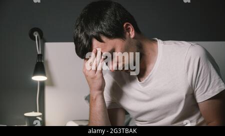 Ein junger Kaukasusmann ist krank und lässt seine Körpertemperatur mit einem elektronischen Thermometer messen. Hochtemperaturkonzept. M Stockfoto