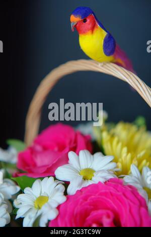 Geschenk Blumenstrauß in einem Weidenkorb mit einem Griff auf einem dunklen Hintergrund. Stockfoto