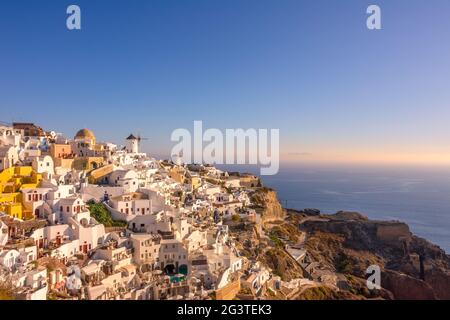 Weiße Häuser und Windmühlen an einem Berghang in Oia Town Stockfoto