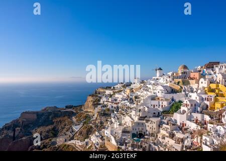 Weiße Häuser und Windmühlen auf einem Berghang in Santorini Stockfoto