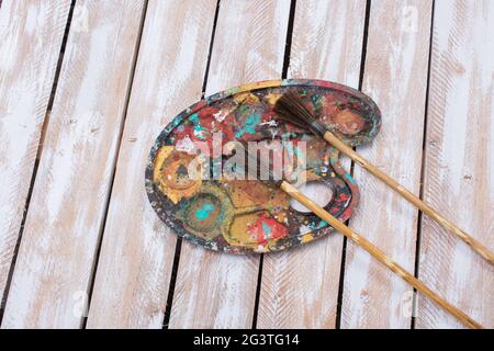 Malpalette und zwei Pinsel auf einer hölzernen Oberfläche Stockfoto