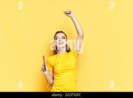 Fröhliche junge Frau, die mit Kopfhörern Musik hört und tanzt, genießt Lieblingslieder Stockfoto