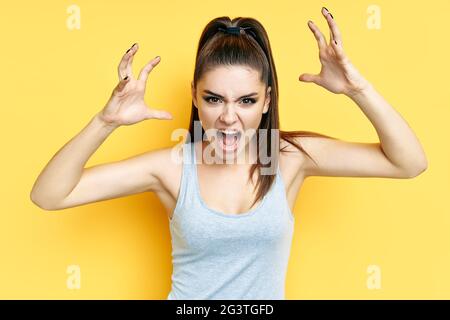 Schreiende, emotional wütende junge Frau Nahaufnahme Porträt über gelben Hintergrund Stockfoto