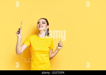 Fröhliche junge Frau, die mit Kopfhörern Musik hört und tanzt, genießt Lieblingslieder Stockfoto