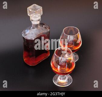Ein Glasdekanter und zwei Gläser Cognac auf schwarzem Hintergrund. Nahaufnahme. Stockfoto