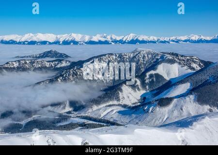 Schneebedeckte Gipfel und Nebel in den Tälern. Luftaufnahme Stockfoto