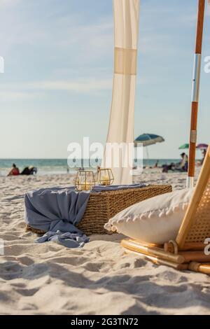 Strandstuhl mit einem Kissen und Kerzen auf einer Wicker-Box in Naples, Florida Stockfoto