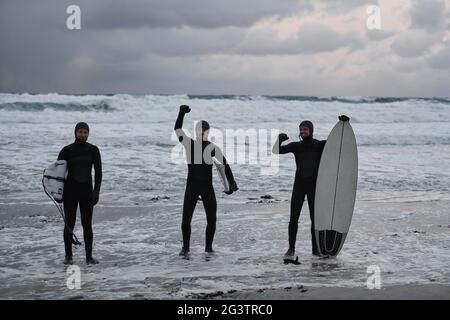 Arktische Surfer gehen nach dem Surfen am Strand vorbei Stockfoto