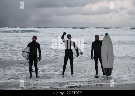 Arktische Surfer gehen nach dem Surfen am Strand vorbei Stockfoto