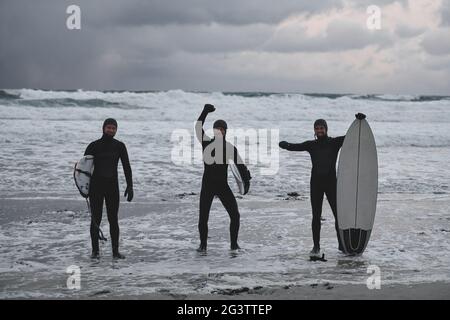 Arktische Surfer gehen nach dem Surfen am Strand vorbei Stockfoto