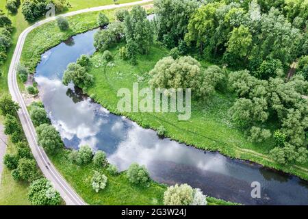 Leerer Radweg entlang grüner Felder und Fluss in der Nähe der Stadt Vorort an sonnigen Sommertag Stockfoto