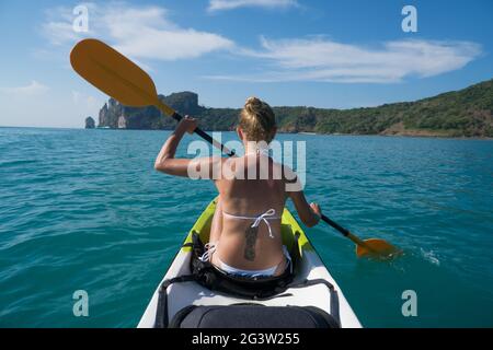 Frau Kajakfahren im türkisfarbenen Meer während des Sommertages Stockfoto