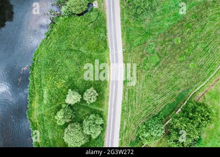 Leere Fahrradspur mit Wanderweg am Flussufer zwischen Bäumen und grünem Gras. Drohnenfoto Stockfoto