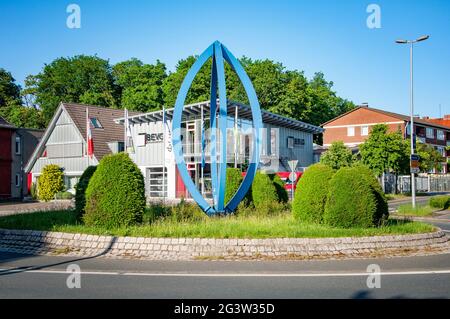BUNDE, DEUTSCHLAND. 12. JUNI 2021. Wunderschöne Aussicht auf die kleine deutsche Stadt. Büro von BEVG Bauelemente. Metallische Installation vor dem Gebäude auf dem Platz. Stockfoto