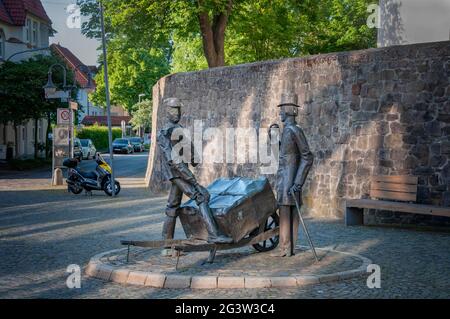 BUNDE, DEUTSCHLAND. 12. JUNI 2021. Wunderschöne Aussicht auf die kleine deutsche Stadt. Metallische Installation von zwei Männern und Schubkarre auf dem Platz Stockfoto