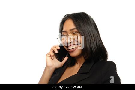 Attraktive junge asiatische Geschäftsfrau, die lächelt, während sie auf einem Mobiltelefon spricht, das isoliert über einer hellgrauen Wand liegt Stockfoto