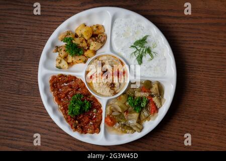 Mischen Sie arabische Speisen auf einem Teller mit vegetarischen Vorspeisen auf Holzboden Stockfoto