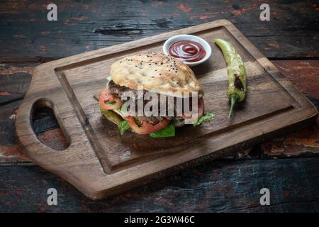 Fleischbällchen-Sandwich mit Tomaten, Zwiebeln und grünem Pfeffer auf rustikalem Holzhintergrund Stockfoto