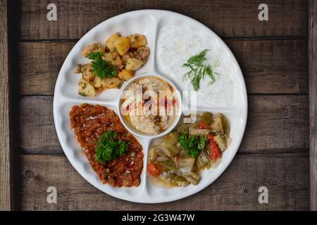 Mischen Sie arabische Speisen auf einem Teller mit vegetarischen Vorspeisen auf rustikalem Holzhintergrund Stockfoto