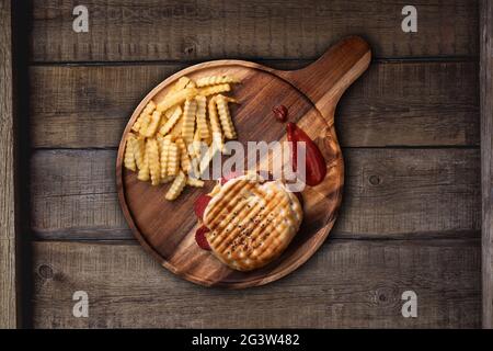 Gegrilltes Panini-Sandwich mit türkischen Würstchen und Käse, serviert mit frischen knusprigen pommes frites auf rustikalem Küchentisch aus Holz Stockfoto