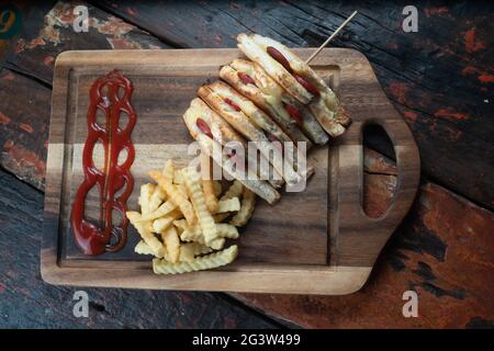 Sandwiches mit türkischer Wurst (Sucuk) und Käse werden auf einem rustikalen Holztisch mit Pommes frites serviert Stockfoto